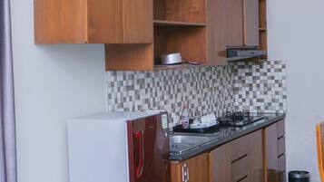 A compact kitchen with wooden cabinets, a tiled backsplash, a built-in stove, and a refrigerator.
