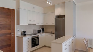 A modern kitchen with white cabinetry, a built-in oven, a microwave, and a stainless steel refrigerator. - Phaedrus Living: Seaside Thalassa Cretan D101 (Platanias)