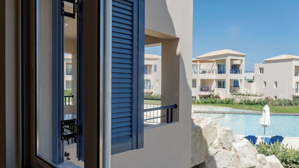 A view from a balcony with a pool and a building in the background. - Phaedrus Living: Seaside Thalassa Cretan D101 (Platanias)