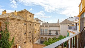 A courtyard with stone buildings, arched walkways, and a balcony overlooking the area. - Cozy 2bd Apartment in Seville. Conde de Ibarra IV (Seville)