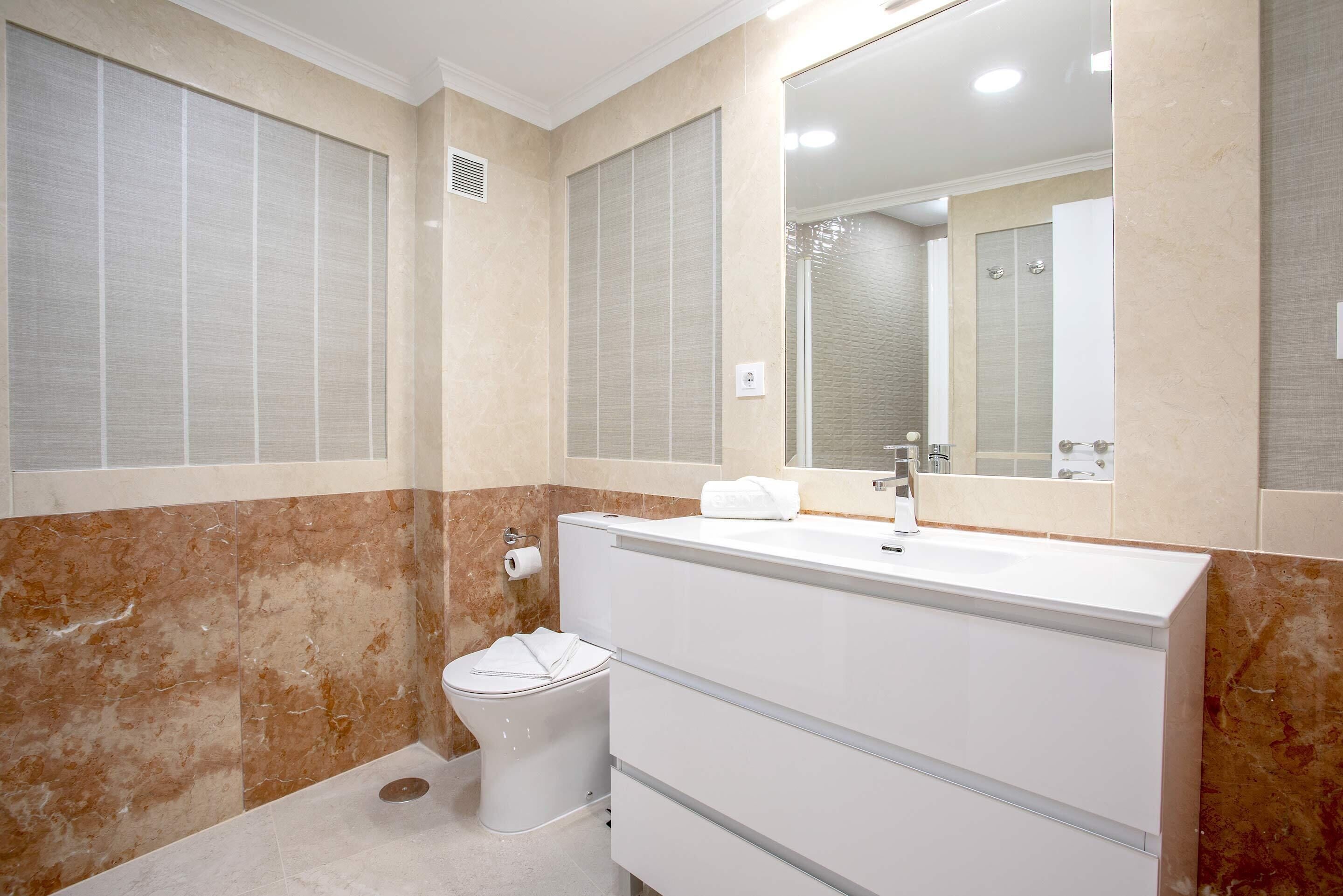 A bathroom with a toilet, a sink, and a mirror.