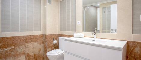 A bathroom with a toilet, a sink, and a mirror.