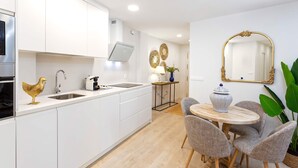 A modern kitchen with white cabinets, a sink, and a dining area with a round table and chairs. - Cozy 2bd Apartment in Seville. Conde de Ibarra IV (Seville)