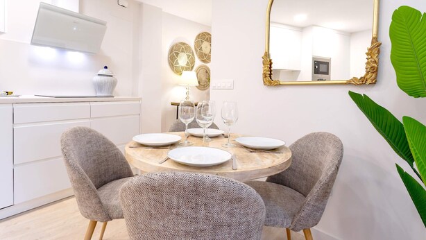A dining area with a round table, two chairs, and a large mirror on the wall. - Cozy 2bd Apartment in Seville. Conde de Ibarra IV (Seville)