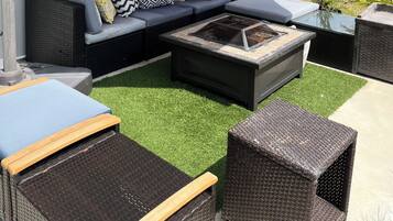 An outdoor patio area with a sectional sofa, a fire pit, and outdoor furniture.