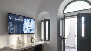 Una cocina moderna con encimera blanca, una silla negra y un televisor mostrando un álbum de música.