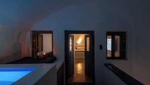 Un pasillo estrecho con una bañera a la izquierda, una puerta que da a un dormitorio a la derecha y un pequeño ventanal al fondo.