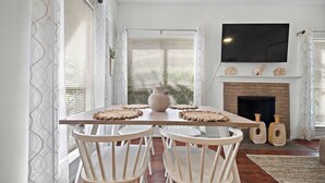 A dining area with a wooden table, white chairs, a large vase, and a fireplace. - Bright 1-bedroom townhome near Texas Medical Center, NRG Stadium, and downtown. (Houston)