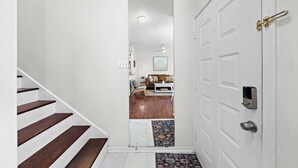 A staircase leading to a living room with a white door, a ceiling fan, and a coffee table. - Bright 1-bedroom townhome near Texas Medical Center, NRG Stadium, and downtown. (Houston)