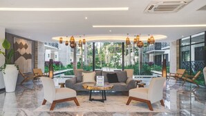 Eine moderne Lobby mit einer zentralen Sitzgruppe, großen Fenstern und Blick auf Grünflächen.