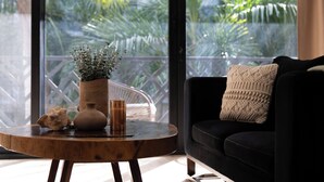 Ein modernes Wohnzimmer mit einem dunklen Sofa, einem runden Holztisch und einem Topf mit Pflanze.
