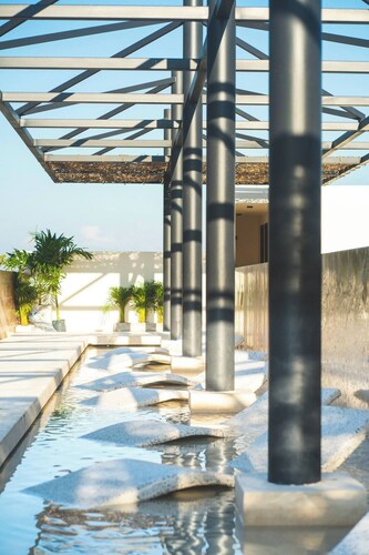 Stay in the heart of Tulum in a modern two-bedroom condo offering rooftop pools with Mayan ruin views, a lush garden patio, and walkable access to the area’s best dining and shopping.