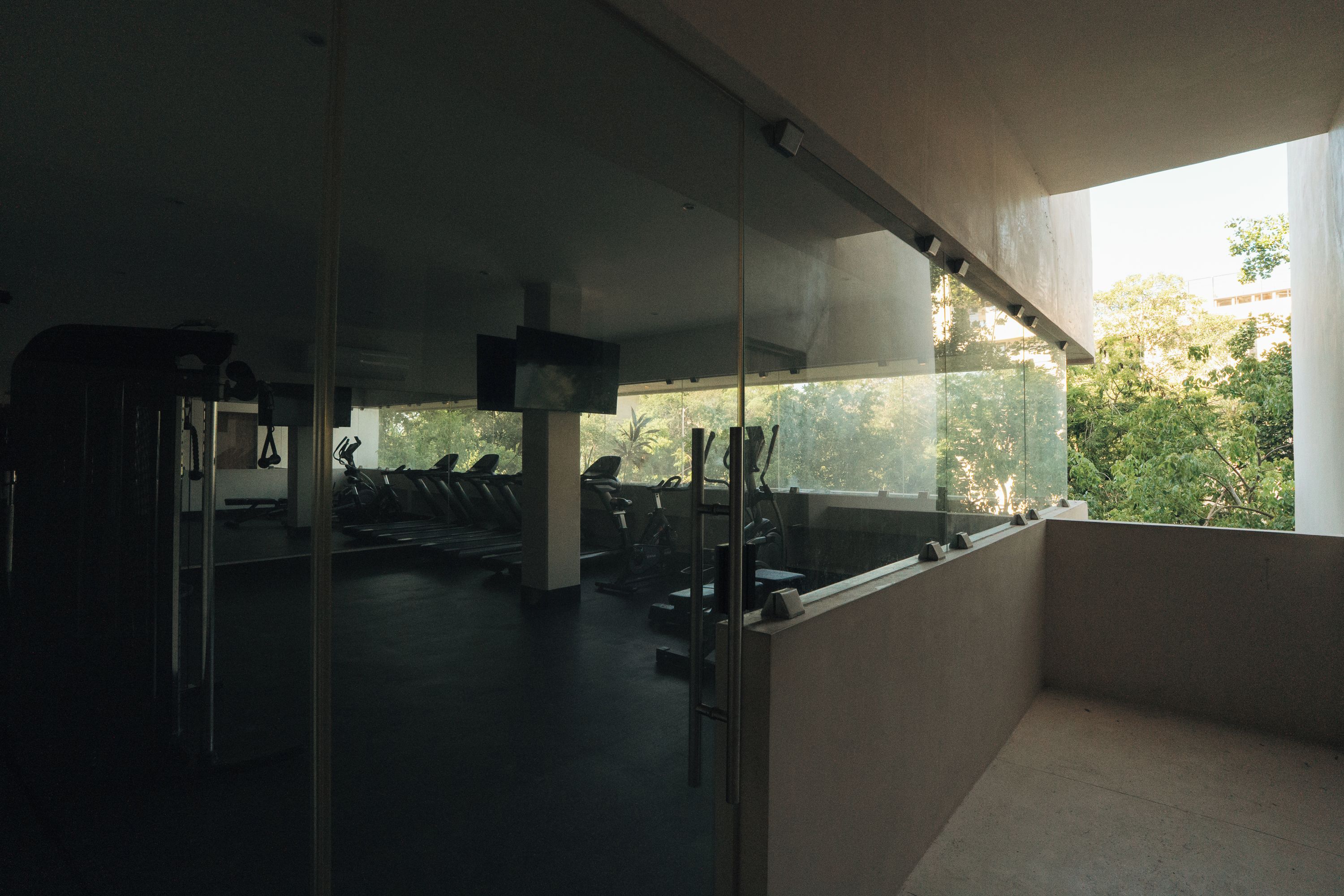 A gym with exercise equipment and a large window overlooking greenery.