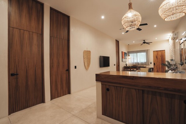A modern kitchen with a wooden island, a flat-screen TV, and a ceiling fan.