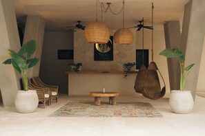 A reception area with wicker hanging lamps, a tiled floor, and potted plants.