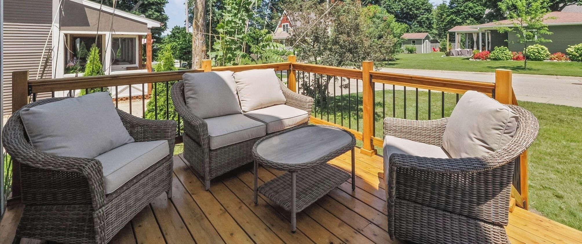 A wooden deck with wicker furniture including two sofas and a small table.