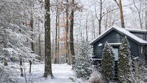 Eine Hütte, umgeben von schneebedeckten Bäumen und einer verschneiten Landschaft.