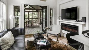 Ein modernes Wohnzimmer mit Kamin, Fernseher und Essbereich mit Blick ins Freie.