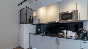 Una cocina moderna con microondas integrado, pileta de acero inoxidable y cafetera.