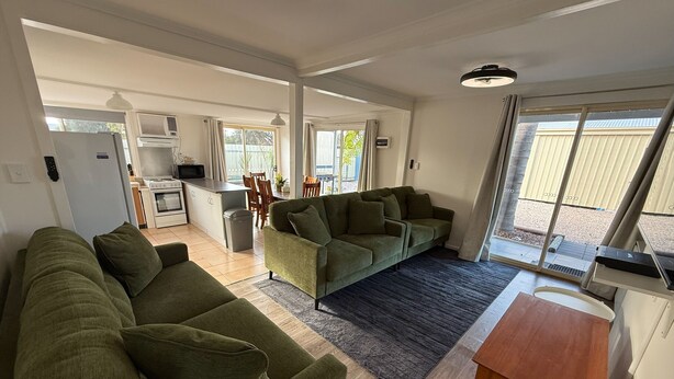 A spacious living area with a sofa set, a dining table, and a kitchen in the background. - 3 by the Sea at Coobowie Unit 3 - 3 bedrooms - dog friendly-Off peak special! (Coobowie)