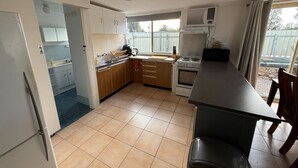 A compact kitchen with a dining area, featuring a stove, oven, sink, and cabinets. - 3 by the Sea at Coobowie Unit 3 - 3 bedrooms - dog friendly-Off peak special! (Coobowie)