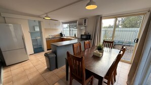 A modern kitchen with a central island, wooden dining table, and chairs. - 3 by the Sea at Coobowie Unit 3 - 3 bedrooms - dog friendly-Off peak special! (Coobowie)