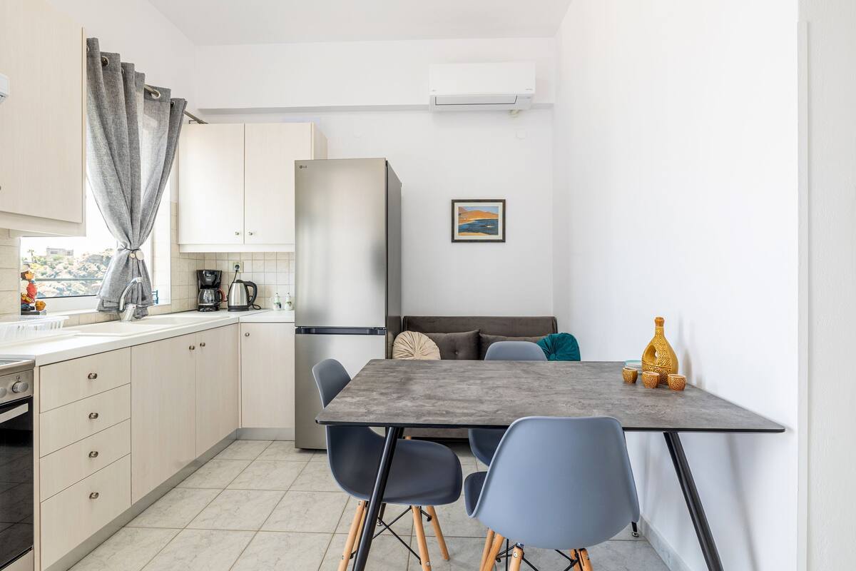 Une cuisine compacte avec un coin repas comprenant une table et des chaises, un réfrigérateur et une machine à café.