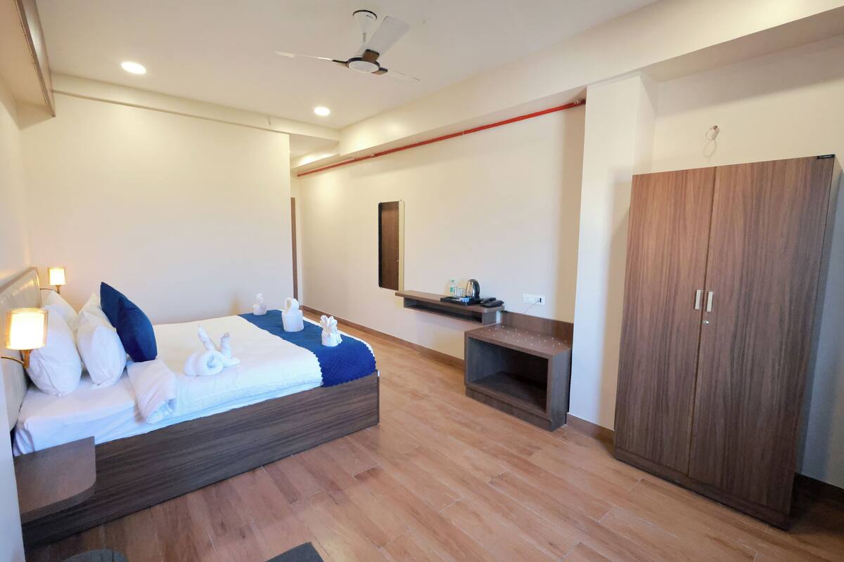Una camera d'hotel moderna con un letto, un comodino, un armadio e un piccolo ripiano con articoli da toilette.