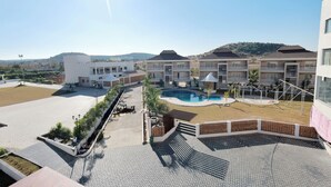 A hotel with a swimming pool, outdoor seating, and a view of the surrounding landscape. - The Grand Rudraksh (Amravati)