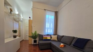 A modern living room with a grey sectional sofa, a small potted plant, and a mirror on the wall.