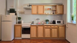 A kitchen with wooden cabinets, a white refrigerator, a stove, a microwave, and a window with a view of greenery.