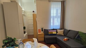 A dining area with a table set for two, a sofa, and a small side table with a plant.