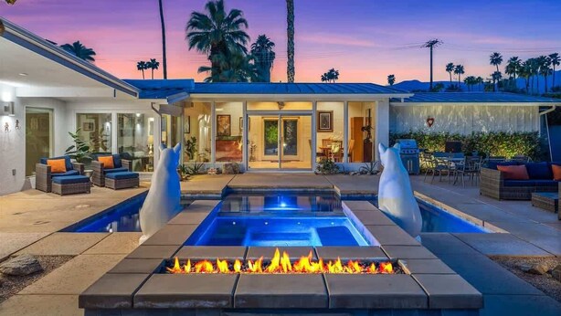 A modern house with a swimming pool, outdoor seating, and a fire pit.