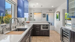 A modern kitchen with a central island, stainless steel appliances, and a view of the outdoors.