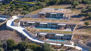 Une villa moderne dotée de plusieurs piscines, d’une architecture en pierre et d’espaces de détente en plein air.