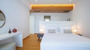 A modern hotel room with a large bed, bedside tables, a desk, and a mirror.