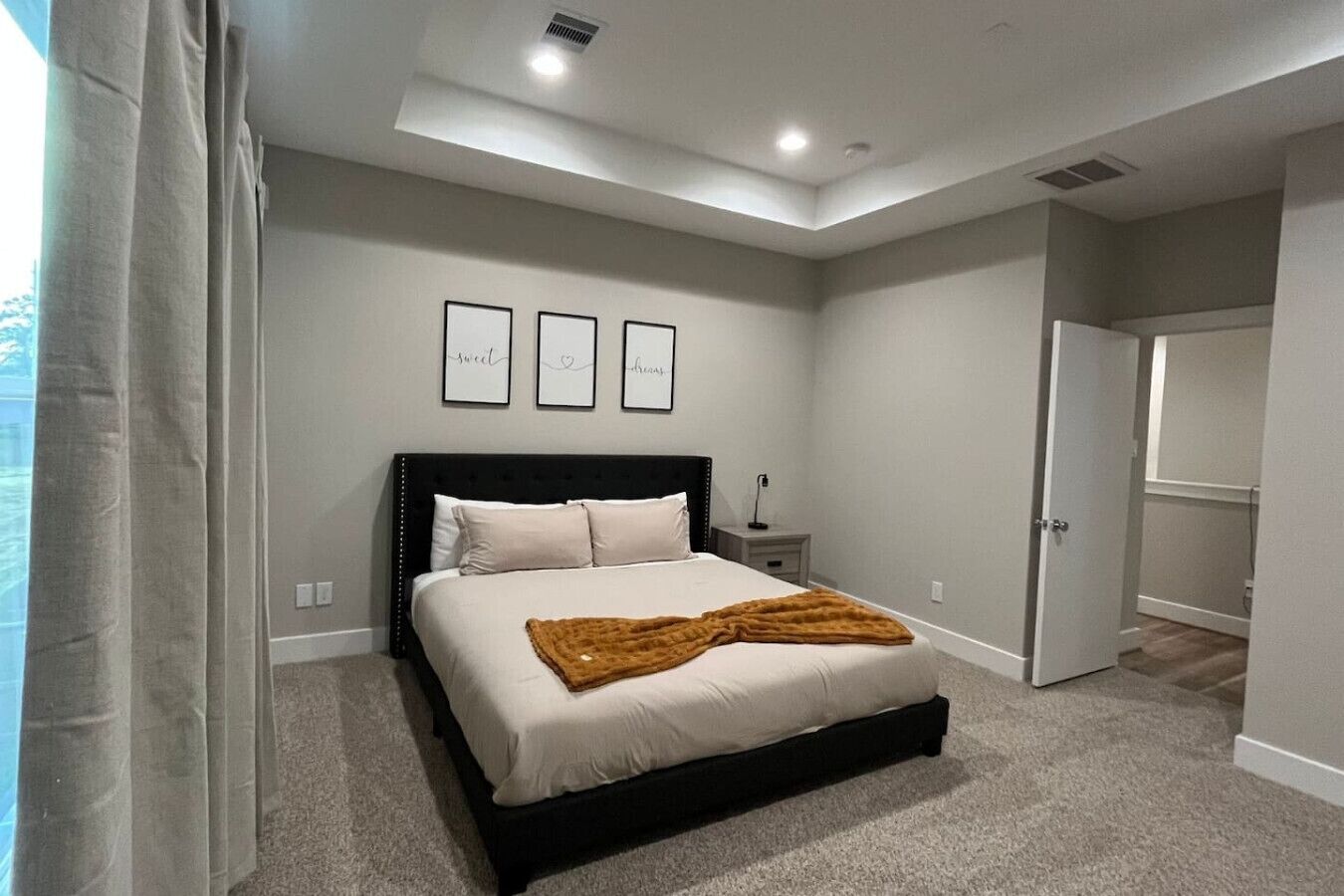 Une chambre à coucher avec un lit, une table de chevet, une porte et un luminaire au plafond.