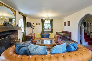 Ein traditionelles Wohnzimmer mit Ledersofa, Holztisch, Kamin, einer Kristallleuchtreiter und einer Treppe.