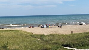 Una playa con arena, algunas tiendas de campaña y gente.
