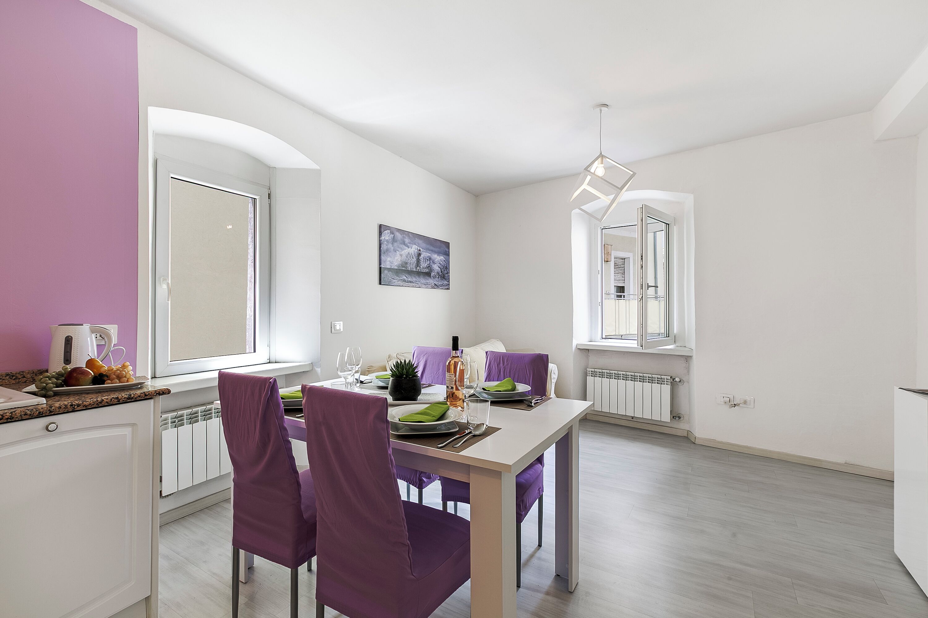 Un comedor moderno con una mesa blanca, sillas moradas y una ventana con vistas.