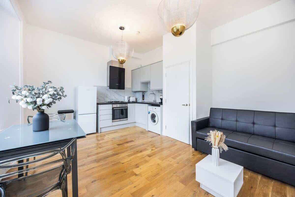 A modern kitchen with white cabinets, a black countertop, and a dining area with a table and chairs.