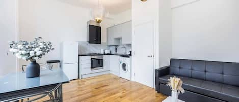 A modern kitchen with white cabinets, a black countertop, and a dining area with a table and chairs.