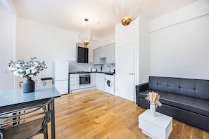 A modern kitchen with white cabinets, a black countertop, and a dining area with a table and chairs.