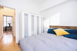 A bedroom with a bed, a wardrobe, and a view of a hallway. - Spacious 1 Bed Islington | BeeMyGuest® (London)