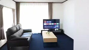 Moderni olohuone, jossa on sohva, sohvapöytä ja litteänäyttöinen televisio.