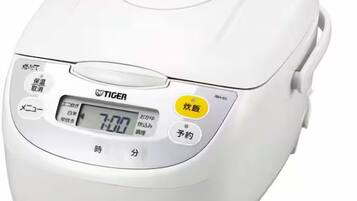 A white rice cooker with a digital display and multiple buttons, including a timer and power settings.