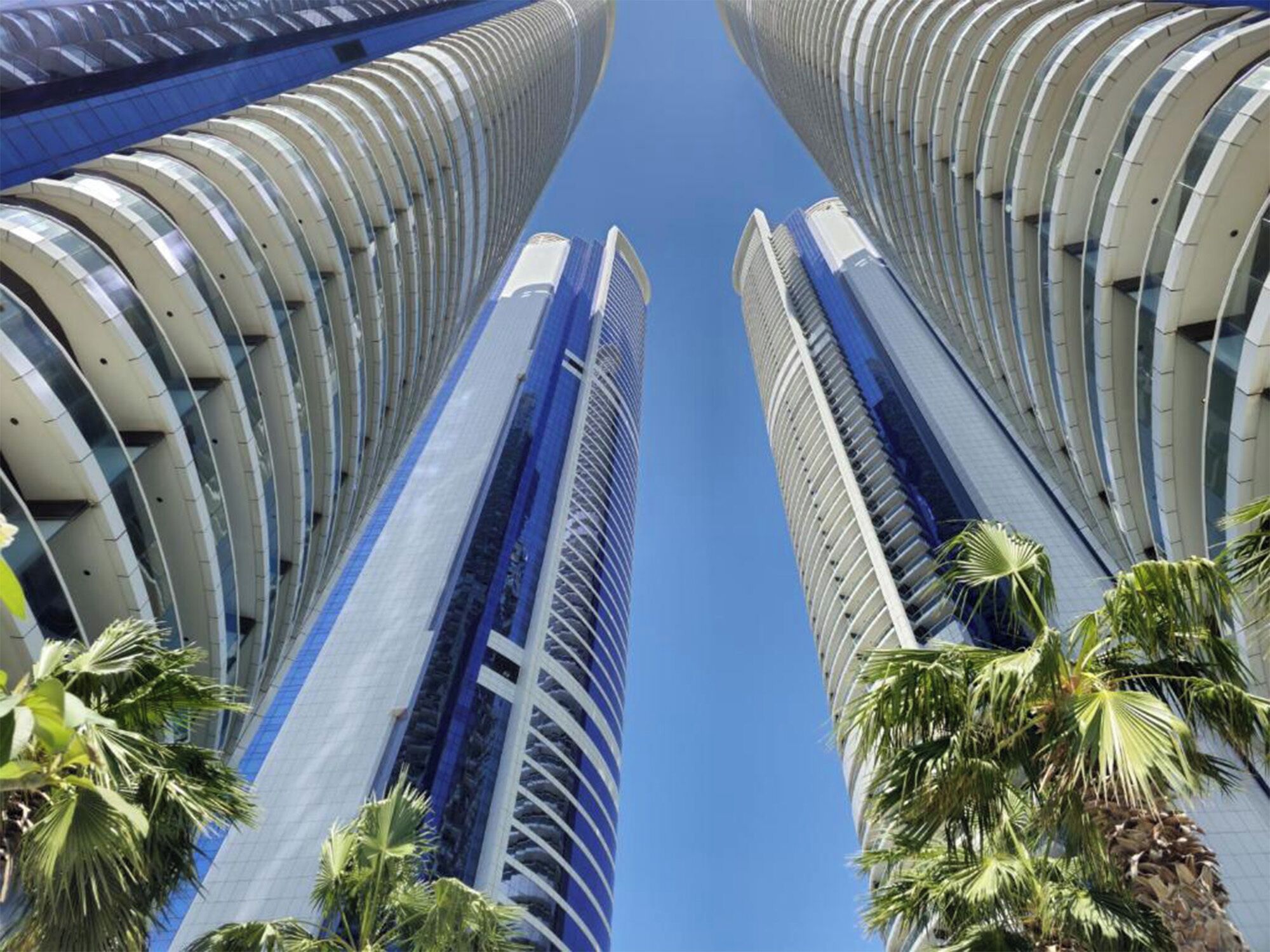 A modern skyscraper with a curved facade and a central vertical blue glass section.