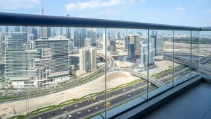 A high-rise building with a view of a cityscape, including modern skyscrapers and a highway. - Cosmos Living 1 Bedroom Paramount Towers (Dubai)