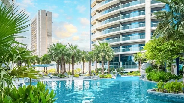 Una piscina rodeada de palmeras y edificios modernos.