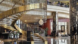 Un lobby lujoso con una imponente escalera en espiral, pisos de mármol y una decoración moderna.
